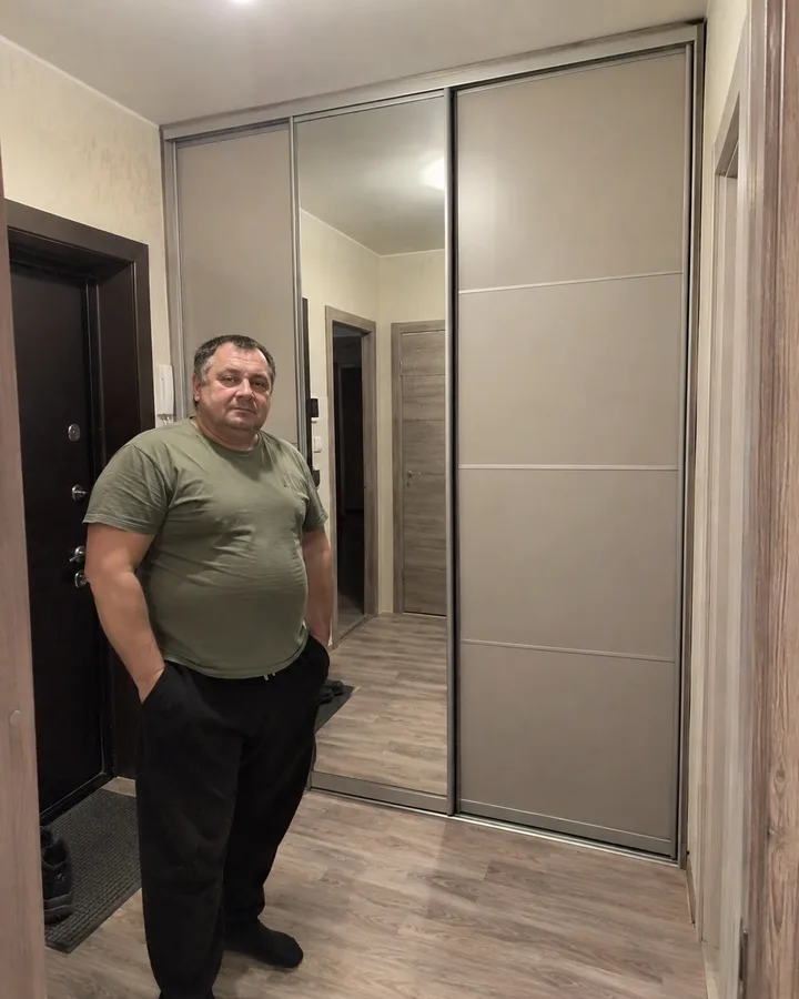 Заказчик рядом со шкафом-купе с зеркальной дверью в прихожей