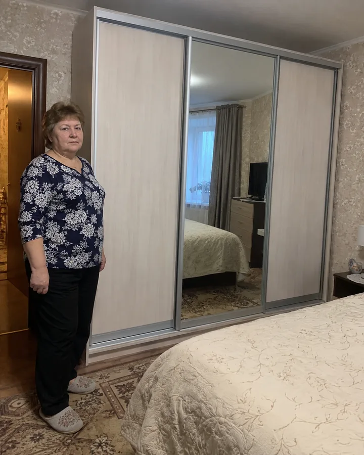 Заказчица рядом со светлым шкафом-купе с зеркальной дверью